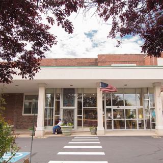 Entrance of a modern building with glass doors and an American flag.