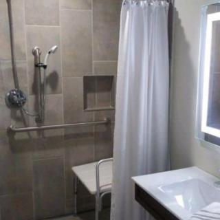 An accessible bathroom featuring a shower with grab bars and a shower seat.