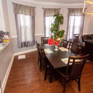 A cozy dining room with a dark wooden table and chairs, featuring elegant curtains and a decorative plant.