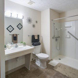 A clean and modern bathroom with a walk-in shower, vanity, and toilet.