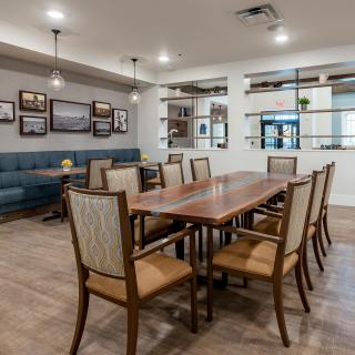 A modern dining room with a large wooden table surrounded by chairs, adorned with stylish lighting and wall art.