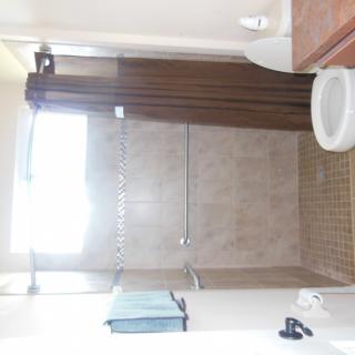 A clean and well-lit bathroom with a shower, sink, and towel.