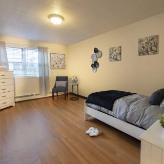 A neatly arranged bedroom with a single bed, dresser, and chair.