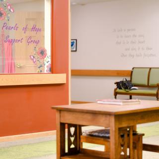 A cozy reception area with a wooden table and seating, complemented by decorative wall art.