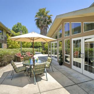A sunny patio with outdoor seating and a garden view.