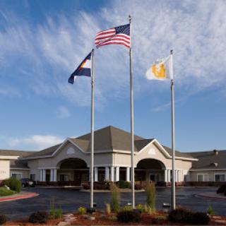 The exterior of a building featuring the American flag, a state flag, and another flag against a clear blue sky.