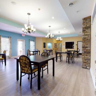 A spacious dining room with multiple tables, chairs, and elegant chandeliers.