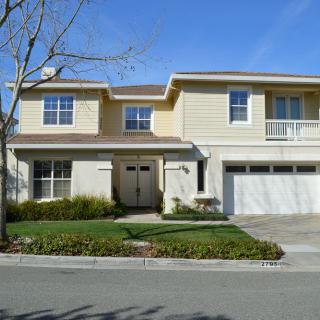 A two-story suburban house with a garage and well-maintained front yard.