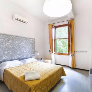 A modern bedroom with a double bed, stylish headboard, and large window with bright curtains.