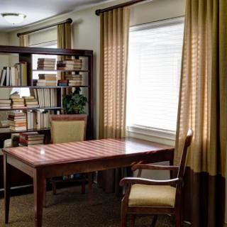 A cozy and organized home office featuring a wooden desk, comfortable chair, and a bookshelf filled with books.