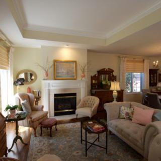 A cozy living room with traditional decor, featuring sofas, a fireplace, and elegant lighting.