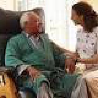 A caregiver attending to an elderly person in a comfortable setting.