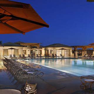 A luxurious outdoor pool area at a resort, beautifully illuminated during the night.