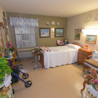 A cozy, decorated bedroom featuring paintings, a wheelchair, and plants.