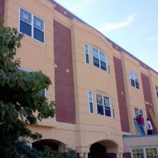 A multi-story apartment building with several windows and a brick exterior.