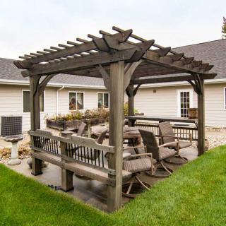 A backyard patio area featuring a wooden pergola with outdoor seating.
