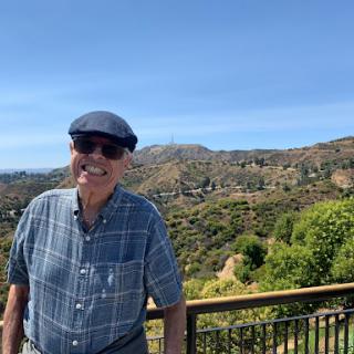 A cheerful man enjoying a sunny day with a beautiful mountain backdrop.