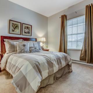 A cozy bedroom interior with a neatly made bed, soft lighting, and decorative artwork on the wall.