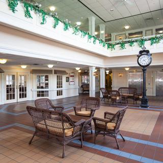 A spacious lobby area with wicker seating and a large decorative clock.