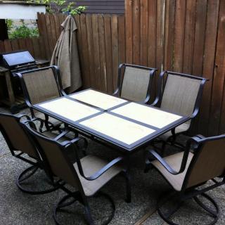 A set of outdoor patio furniture with a table and six chairs arranged neatly.