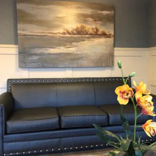 A stylish interior featuring a sleek black sofa, elegant wall art, and vibrant flowers.