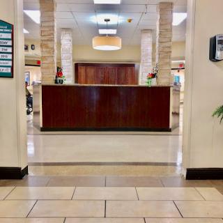 A view of a reception area within a healthcare facility, featuring a wooden reception desk and tiled floors.