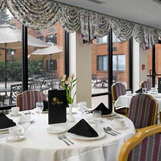 An elegantly set dining table in a restaurant with a view of the outdoor patio.