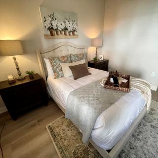 A cozy bedroom with a neatly made bed, elegant lamps on nightstands, and a decorative tray.