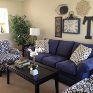 A cozy living room with a blue sofa, patterned armchairs, and stylish decor.