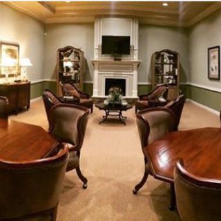 A luxurious living room with elegant leather chairs and a central fireplace.