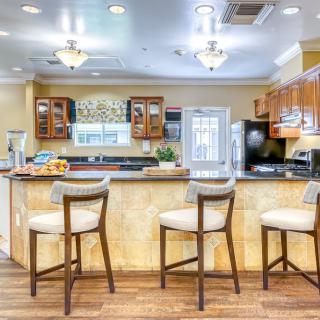 A modern kitchen interior featuring bar stools at a large countertop with wooden flooring.