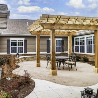 A cozy outdoor patio with a wooden pergola and seating area.