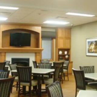 A modern dining room with multiple tables and chairs, featuring a fireplace and a wall-mounted television.
