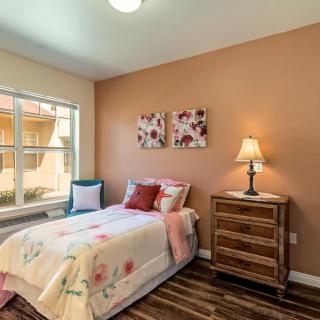 Cozy bedroom with a single bed, side table, lamp, and floral decor.
