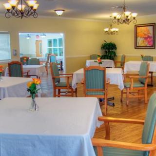 A well-lit dining room with neatly arranged tables and chairs, adorned with flowers.