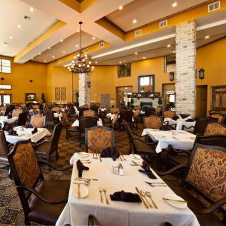Elegant restaurant dining room with well-arranged tables and chairs, featuring classic decor and a chandelier.