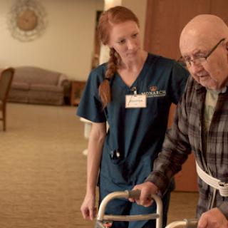 A nurse assists an elderly patient with a walker, providing support and care in a rehabilitation setting.