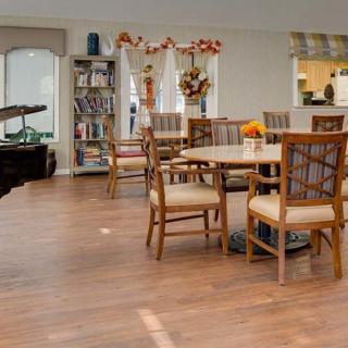 A cozy dining area with wooden tables and chairs, adorned with decorations and a nearby bookshelf.