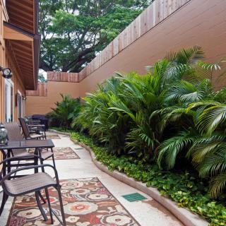 A cozy outdoor patio area with chairs and tables surrounded by lush greenery.