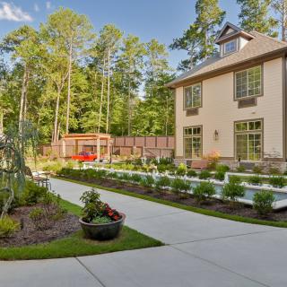 A modern house with a landscaped garden and driveway surrounded by trees.