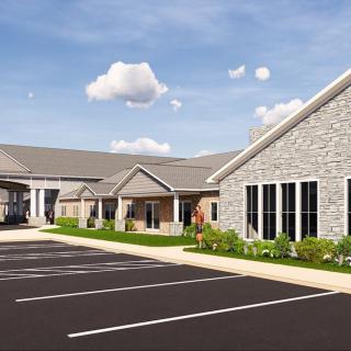 A modern commercial building with a spacious parking area under a partly cloudy sky.