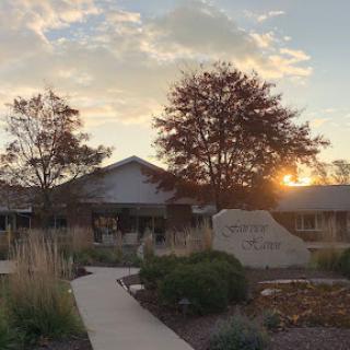 A serene sunset over a peaceful building surrounded by trees and blooming foliage.