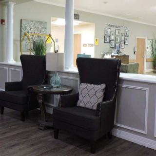 A modern lobby seating area with two dark armchairs, a small table, and decorative elements.