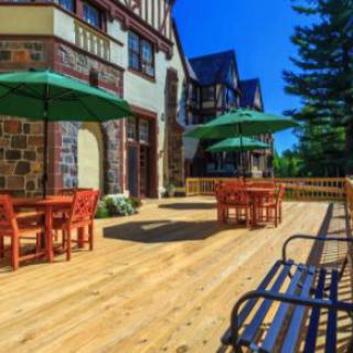 A sunny outdoor patio with tables, chairs, and umbrellas next to a charming building.
