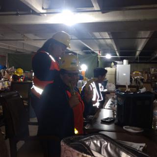 Workers wearing safety helmets and vests collaborate in a well-lit construction site.