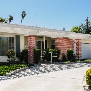 A suburban single-story house with a driveway and landscaped front yard.