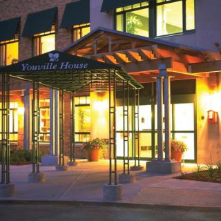 The illuminated entrance of a hotel under an awning at night.