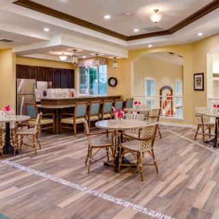 A modern kitchen and dining area featuring wooden flooring, tables, and a bar counter.