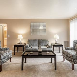 A cozy living room with a sofa, armchairs, and coffee table, warmly lit by lamps on side tables.