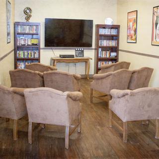 A cozy entertainment area with a television, bookshelves, and comfortable seating.